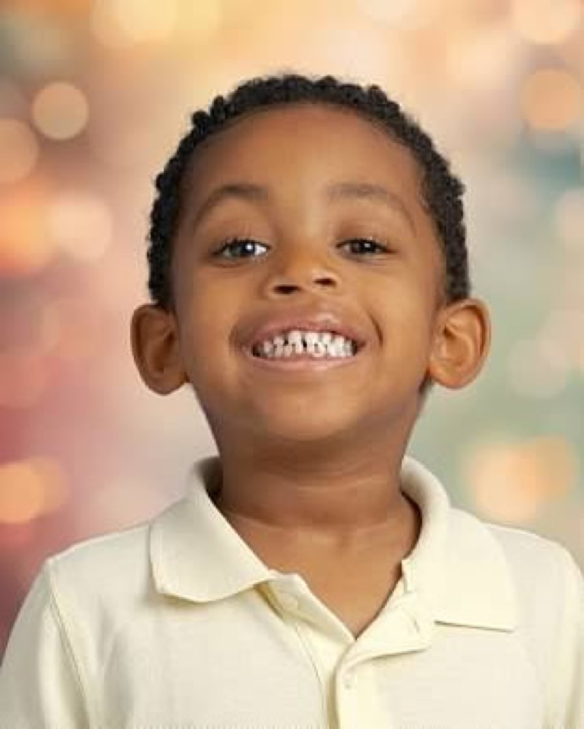 Yonas school portrait — close-up headshot with a big smile wearing a cream polo shirt against a soft bokeh background