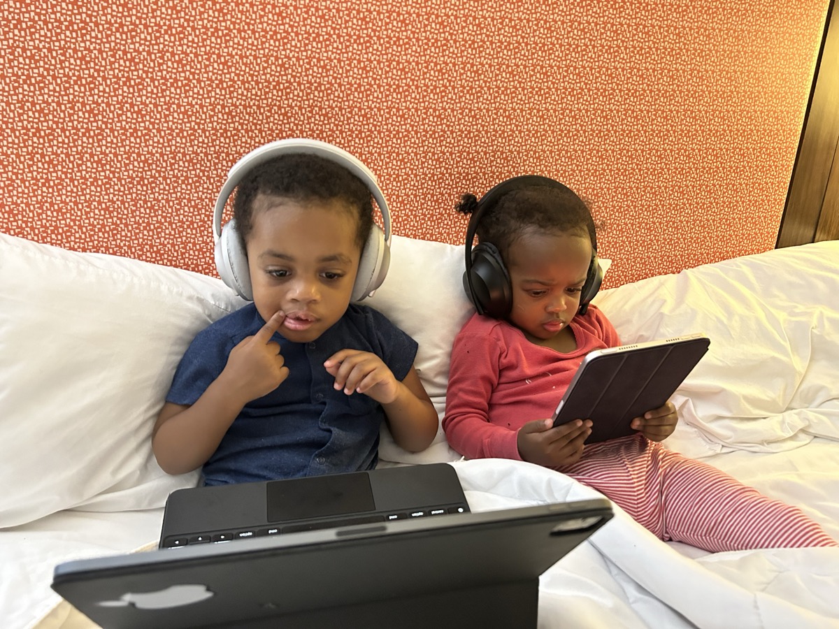 Yonas and his twin sister as newborns in matching white outfits, nestled together on a soft blanket with a small stuffed animal