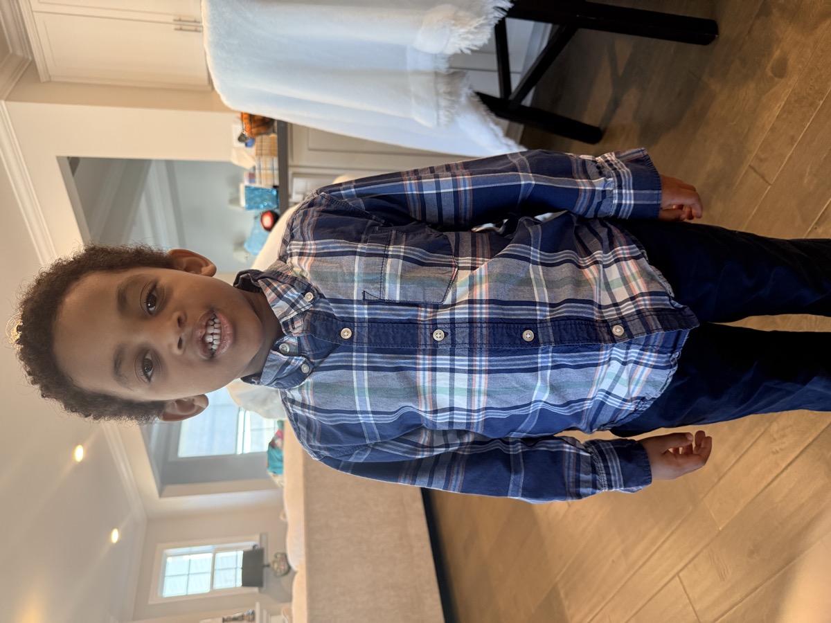 Yonas and his twin sister at a birthday party with balloons behind them, Yonas in a button-up shirt looking excited